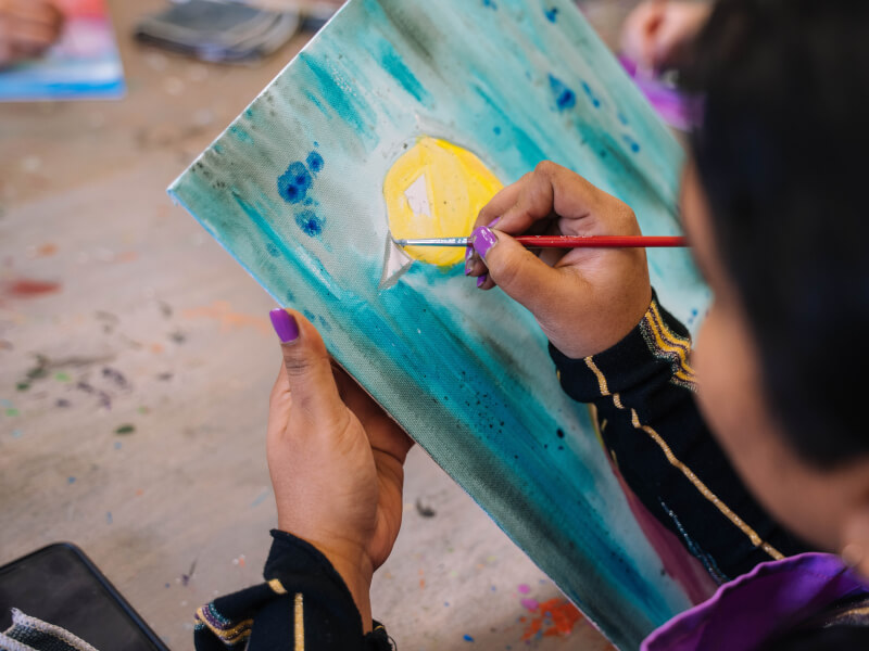 A person adds details to their peacock watercolour painting.
